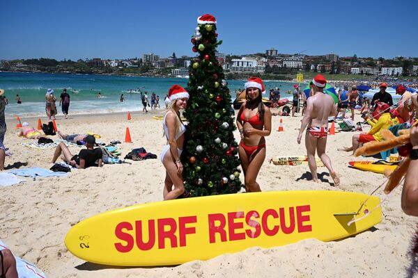 Turistas posam para foto usando gorro de Papai Noel ao lado de uma árvore de Natal na praia de Bondi em Sydney, em 25 de dezembro de 2018 - Sputnik Brasil