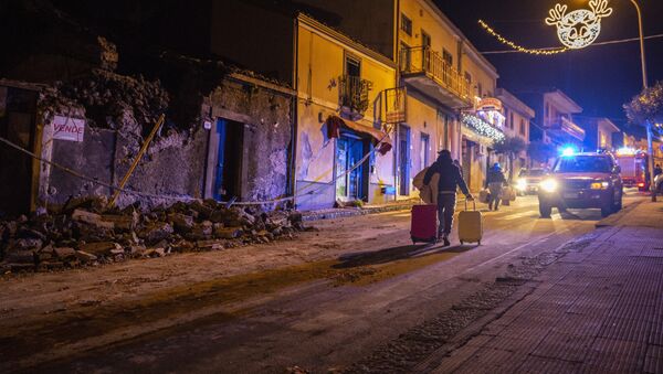 Homem carrega pertences em meio a escombros em Fleri, na Sicília, nesta quarta-feira, 26 de dezembro de 2018 - Sputnik Brasil