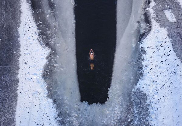 Imagem tirada de cima de um homem nadando em um lago congelado, com temperaturas abaixo de -20 graus Celsius, em Shenyang, na província de Liaoning, nordeste da China - Sputnik Brasil