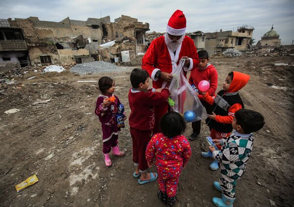 Homem vestido de Papai Noel distribui presentes para as crianças, no Iraque - Sputnik Brasil