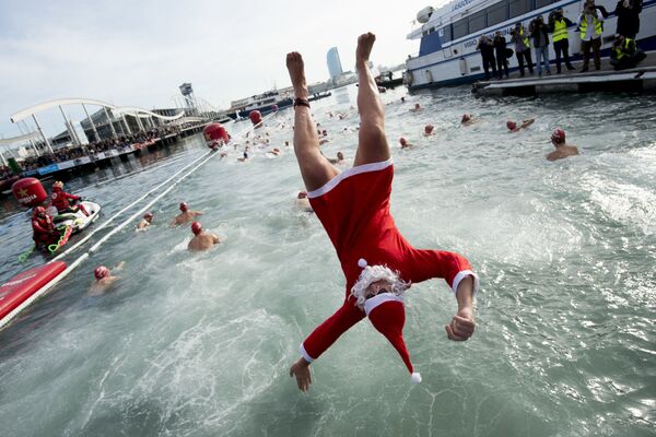 Participante vestindo roupa de Papai Noel pula na água durante a Copa de Natal, em Barcelona - Sputnik Brasil