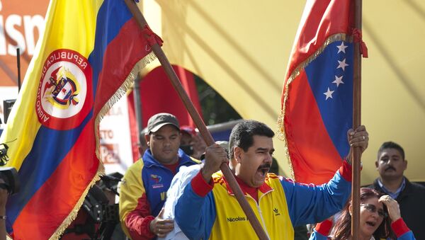 Venezuela's President Nicolas Maduro holds up a Colombian national flag, left, alongside his country's national flag, during a rally in support of closing the Colombian border, in Caracas, Venezuela, Friday, Aug. 28, 2015. - Sputnik Brasil