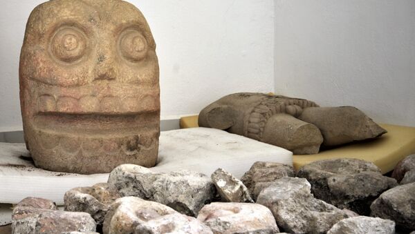 Duas esculturas de pedra parecidas com caveiras e uma de tronco representando o deus Xipe Totec encontradas durante as escavações no estado de Puebla, México - Sputnik Brasil