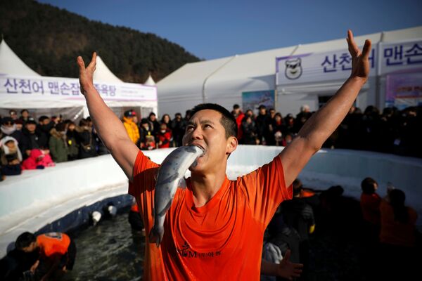 Um homem satisfeito por ter apanhado um peixe com as mãos durante um festival de truta na cidade sul-coreana de Hwacheon - Sputnik Brasil