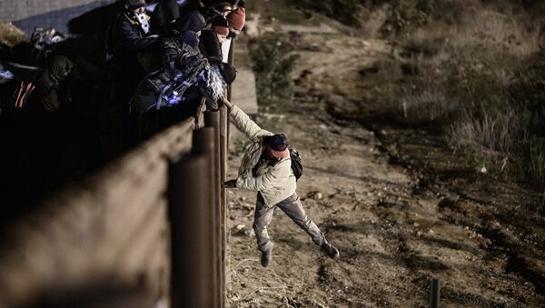 Um migrante em Tijuana, México pula a fronteira para entrar na cidade americana de San Diego, na Califórnia. - Sputnik Brasil