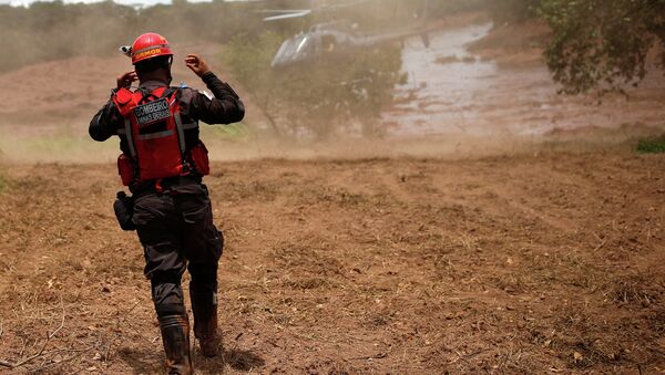 Um bombeiro gesticula perto de um helicóptero de resgate após uma barragem de rejeitos da mineradora brasileira Vale SA explodir em Brumadinho. - Sputnik Brasil