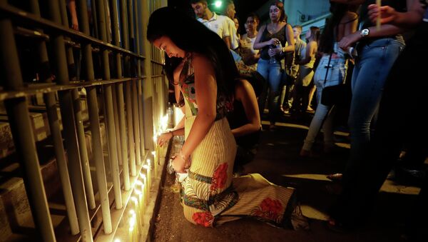 Mulher colocando velas em homenagem às vítimas em Brumadinho (MG) - Sputnik Brasil