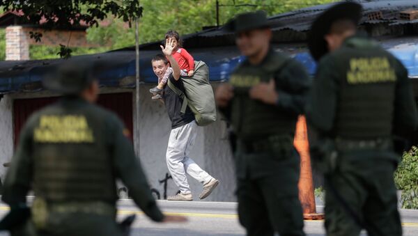 Imigrante da Venezuela acena a policiais enquanto entra na Colômbia. - Sputnik Brasil
