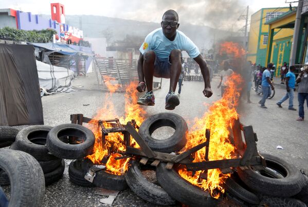 Manifestante salta sobre uma barricada em chamas durante protesto contra o governo nas ruas de Porto Príncipe, no Haiti, em 10 de fevereiro de 2019 - Sputnik Brasil