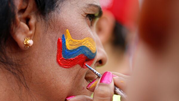 Manifestantes pintam bandeira venezuelana no rosto de uma mulher durante manifestação contra o governo do presidente venezuelano Nicolás Maduro, em Caracas, 26 de outubro de 2016 - Sputnik Brasil