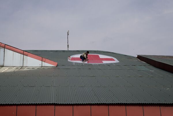 Funcionário desenha o emblema da Cruz Vermelha no telhado do hospital SMHS na Caxemira em meio à escalada nas relações indo-paquistanesas - Sputnik Brasil