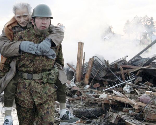 Soldado carrega vítima atingida por terremoto e tsunami na cidade de Natori, província de Miyagi, no Japão, 12 de março de 2011 - Sputnik Brasil