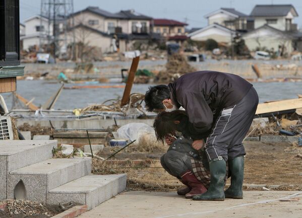 Pessoas chorando em frente a uma casa danificada na cidade de Watari, na província japonesa de Miyagi, 14 de março de 2011 - Sputnik Brasil