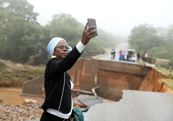 Mulher tira selfie em uma ponte sobre o rio Umvumvu destruída pela passagem do ciclone tropical Idai em Zimbabué - Sputnik Brasil