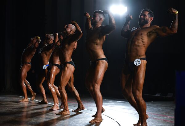 Homens marcam músculos dos braços no palco no campeonato aberto de fisiculturismo - Sputnik Brasil