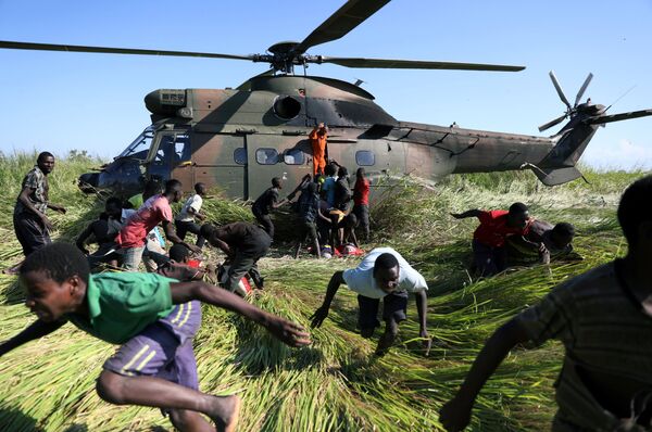 Moradores locais fogem da aterrissagem de um helicóptero da Força Nacional de Defesa da África do Sul que traz ajuda humanitária para um povoado afetado pelo ciclone, em Moçambique - Sputnik Brasil
