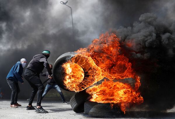 Manifestante palestino com pneu ardendo durante confrontos com tropas israelenses perto de povoação judia de Beit El, na Cisjordânia - Sputnik Brasil