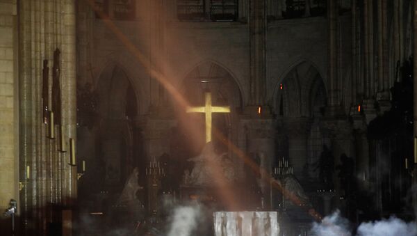 Fumaça se forma em torno do altar em frente à cruz do interior da Catedral de Notre Dame enquanto incêndio continua queimando em Paris, França, 16 de abril de 2019 - Sputnik Brasil