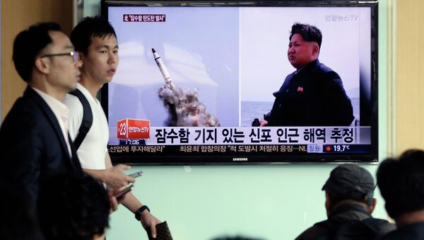 Programa de TV na Coreia do Sul mostra images veiculadas pelo jornal norte-coreano Rodong Sinmun do suposto lançamento submarino de um míssil balístico da Coreia do Norte, ao lado do líder norte-coreano Kim Jong-un, em 9 de maio de 2015 - Sputnik Brasil