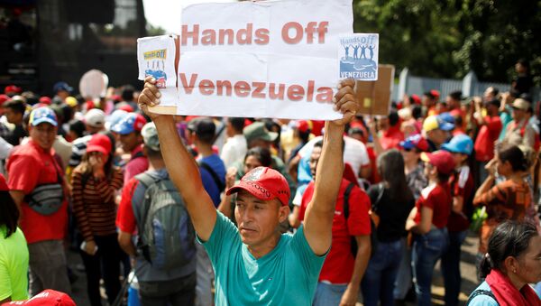 Un partidario de Nicolás Maduro con la pancarta Manos fuera de Venezuela - Sputnik Brasil