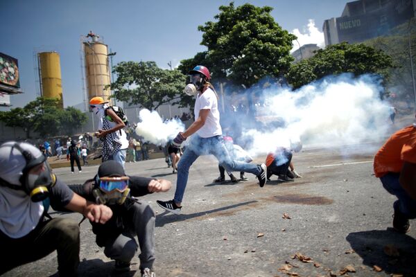 Opositores a Maduro se esquivam de gás lacrimogêneo perto da base aérea La Carlota, em Caracas - Sputnik Brasil