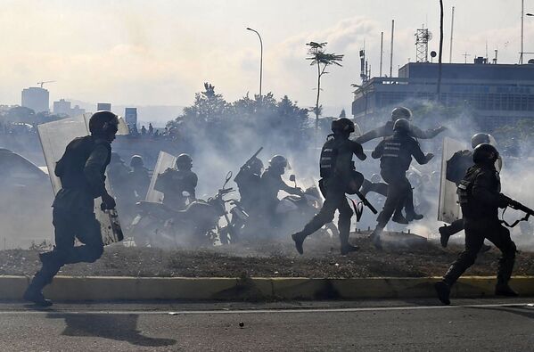 Soldados da Guarda Nacional Bolivariana são cobertos por gás lacrimogênio perto da base aérea La Carlota, em Caracas - Sputnik Brasil