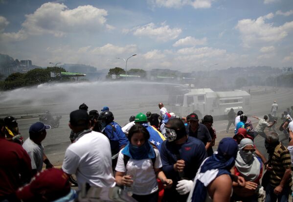 Veículo blindado jorra jatos de água para dispersar manifestantes opositores ao governo de Maduro perto da base aérea La Carlota, em Caracas - Sputnik Brasil