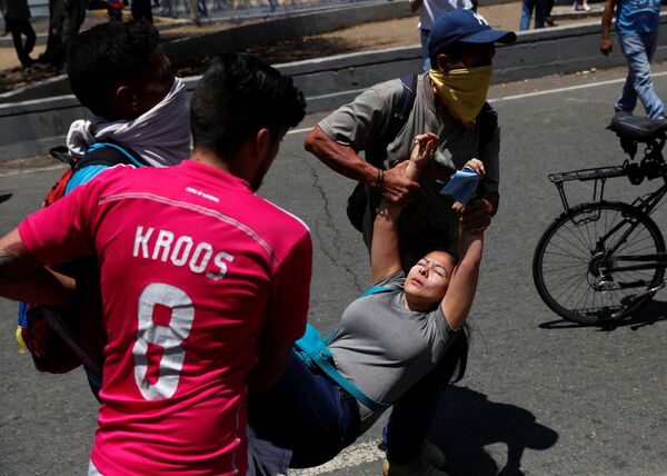 Pessoas carregam jovem ferida durante protestos perto da base aérea La Carlota, em Caracas - Sputnik Brasil