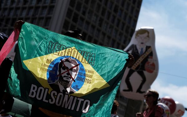 Sindicalista segura uma bandeira do Brasil com a imagem do presidente do Brasil, Bolsonaro, onde se lêvergonha, não à reforma da previdência e tire as mãos dos nossos direitos durante passeata de 1º de Maio. - Sputnik Brasil