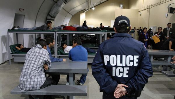 Um oficial da Imigração e Fiscalização Aduaneira (ICE) observa um grupo de 116 imigrantes salvadorenhos que esperam ser deportados, na instalação de detenção em Raymondville, Texas. - Sputnik Brasil