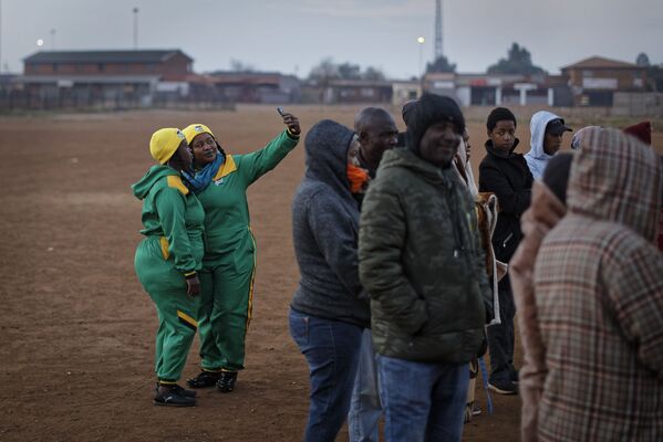 Dois apoiadores do Congresso Nacional Africano tiram selfies enquanto fazem fila para votar no povoado de Bekkersdal a oeste de Johanesburgo, na África do Sul - Sputnik Brasil