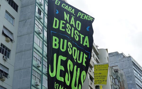 Manifestante carrega bandeirão com a frase Ei cara, não desista. Busque Jesus. - Sputnik Brasil
