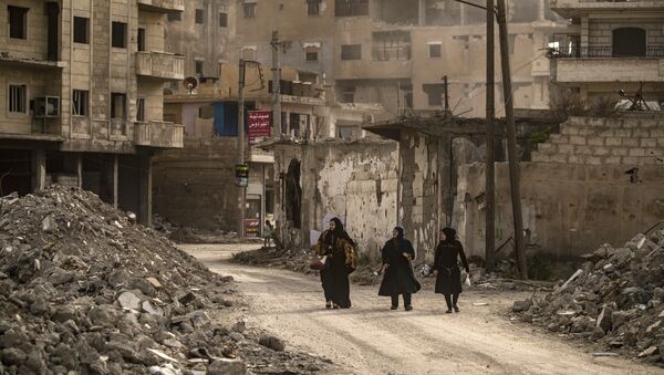 Mulheres caminham em meio a ruínas em Raqqa, cidade localizada no norte da Síria, 1º de maio de 2019 - Sputnik Brasil