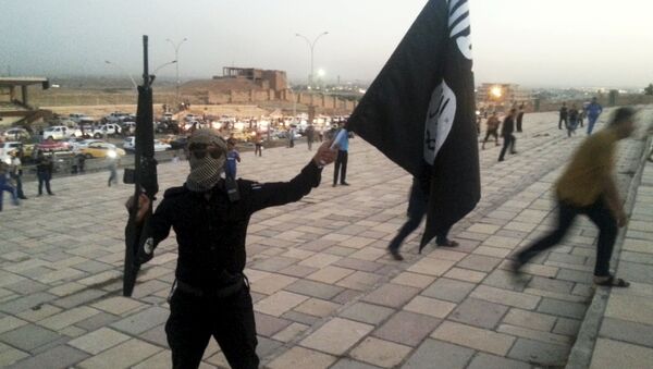 Um combatente do Daesh segura uma bandeira do grupo terrorista e uma arma na cidade de Mosul, no Iraque. - Sputnik Brasil