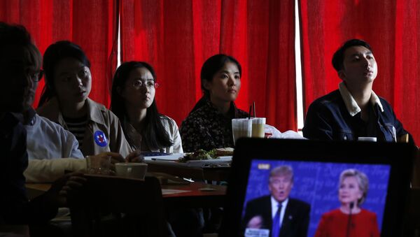 Estudantes chineses assistem a transmissão ao vivo do debate presidencial entre a candidata democrata Hillary Clinton e o candidato republicano à presidência, Donald Trump, em um café em Pequim. - Sputnik Brasil