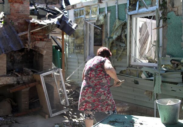 Mulher limpa quintal de casa atingida por tiros em Donetsk
 - Sputnik Brasil