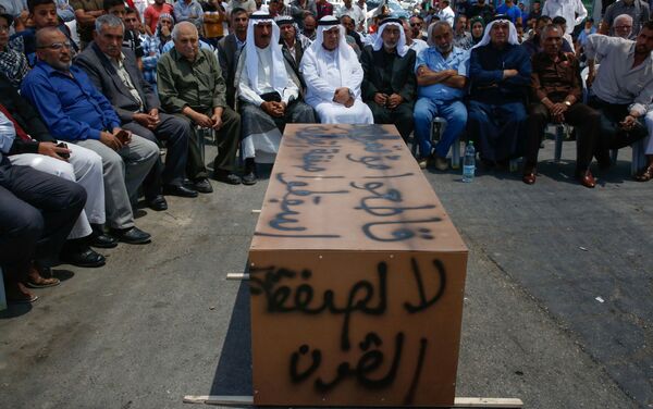 Palestinos sentados perto de um caixão improvisado com palavras Não para o acordo do século, durante protestos contra encontro liderado pelos EUA em Bahrein sobre conflito palestino-israelense, na aldeia de Yatta, perto da Cisjordânia, 24 de junho de 2019 - Sputnik Brasil
