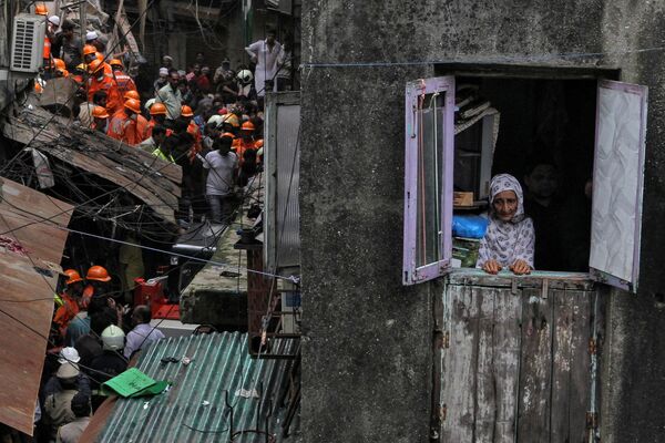 Habitante local olhando pela janela enquanto socorristas procuram sobreviventes após o colapso de um prédio em Mumbai, na Índia - Sputnik Brasil