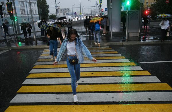 Jovem atravessando na faixa de pedestre com chuva, em Moscou - Sputnik Brasil