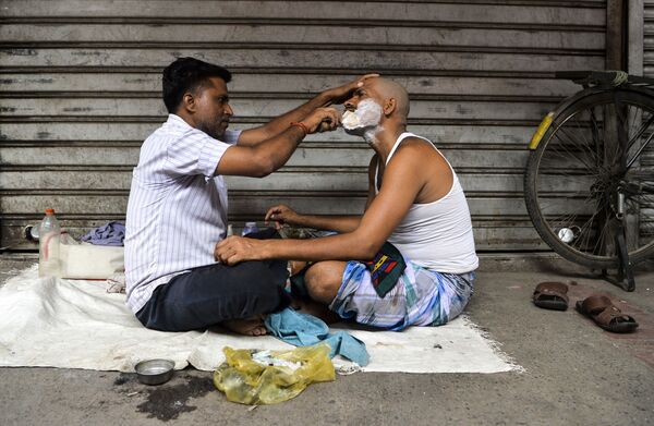 Barbeiro escanhoando o rosto de cliente no bairro velho de Nova Deli, na Índia - Sputnik Brasil