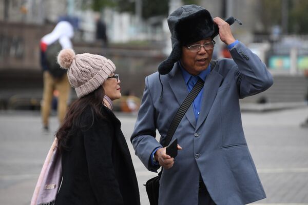 Turistas estrangeiros se agasalham com gorros na praça Manezhnaya durante o tempo frio em Moscou
 - Sputnik Brasil