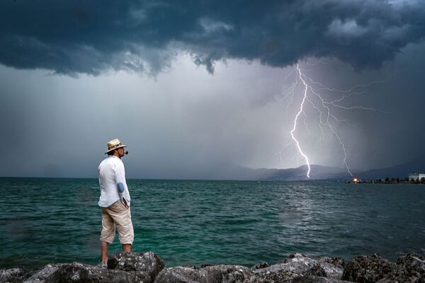 Homem e relâmpago ao fundo no lago de Genebra, na Suíça
 - Sputnik Brasil