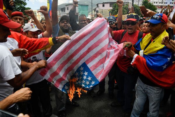 Apoiadores do governo venezuelano queimam bandeira estadunidense durante a manifestação contra as sanções dos EUA em Caracas - Sputnik Brasil