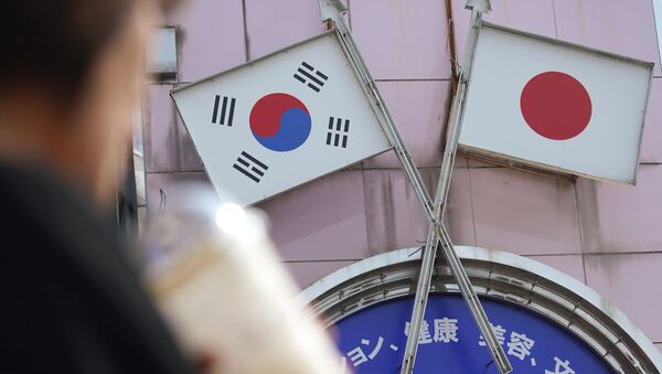 Mulher caminha enfrente anúncio com as bandeiras sul-coreana e japonesa - Sputnik Brasil