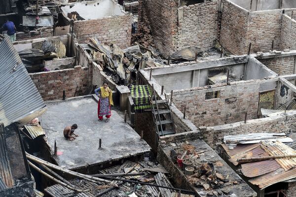 Criança brinca no telhado de uma casa destruída pelo fogo em uma favela de Daca, capital do Bangladesh - Sputnik Brasil