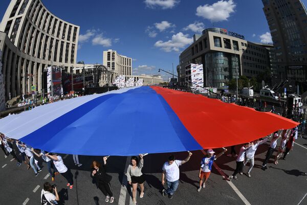 Participantes da festa do Dia da Bandeira Nacional da Rússia com uma enorme bandeira russa em Moscou - Sputnik Brasil