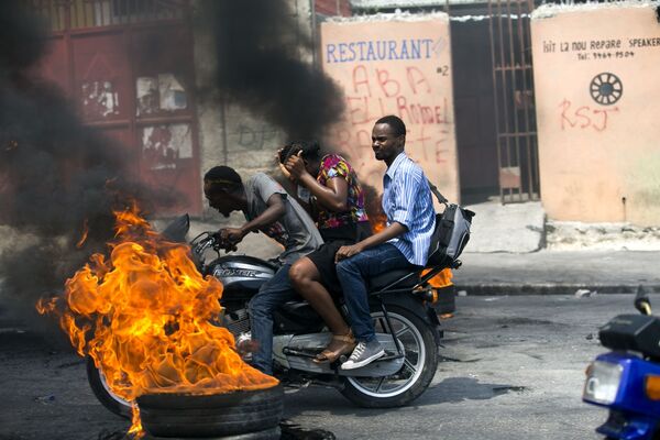 Mototáxi passando por pneu em chamas em Porto Príncipe, no Haiti, 16 de setembro de 2019 - Sputnik Brasil