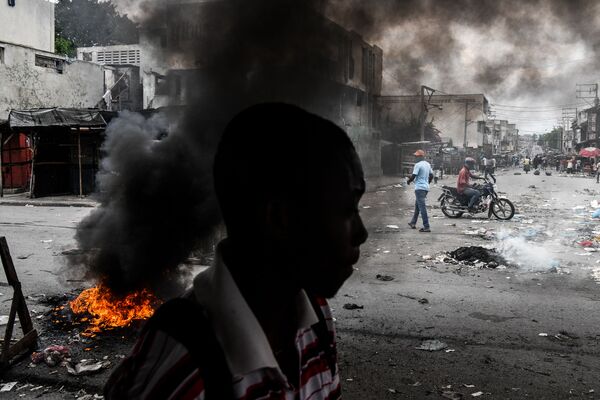 Homem passando em frente a pneus queimados por manifestantes durante protestos contra o presidente haitiano Jovenel Moise em Porto Príncipe, capital do Haiti - Sputnik Brasil