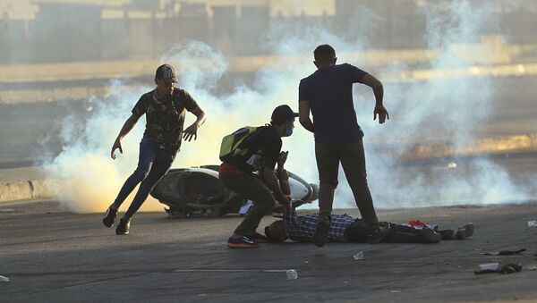Manifestantes correm para ajudar um homem ferido durante protesto em 5 de outubro de 2019 contra o governo em Bagdá, no Iraque. Protestos começaram na terça-feira em diversas cidades do país contra corrupção e desemprego. - Sputnik Brasil
