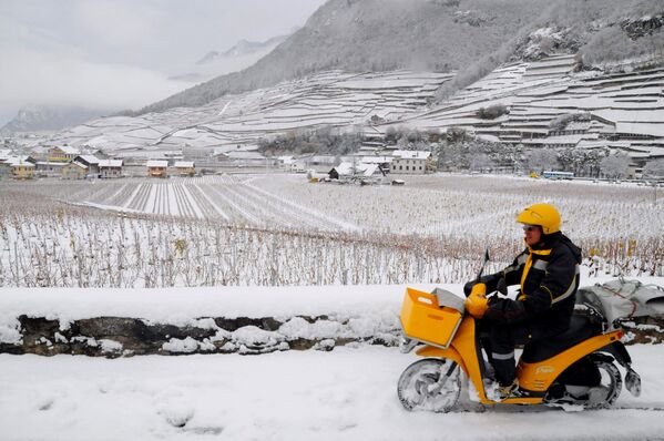Carteiro dirige sua moto sobre a neve fresca em Aigle, na Suíça - Sputnik Brasil